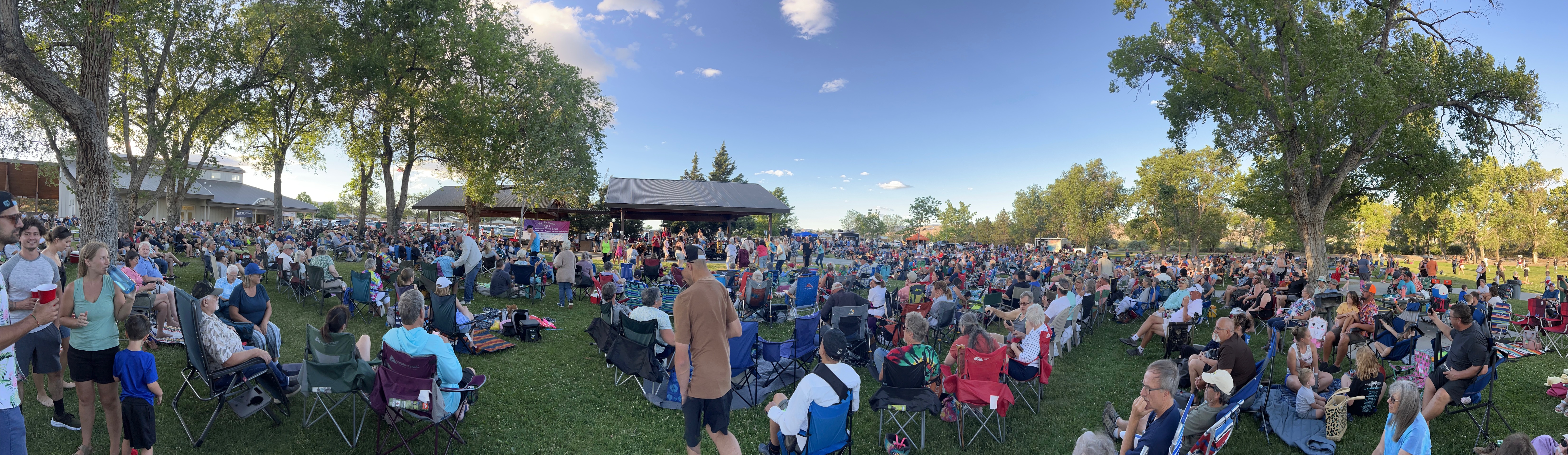 People in lawn chairs on grass watching a concert stage